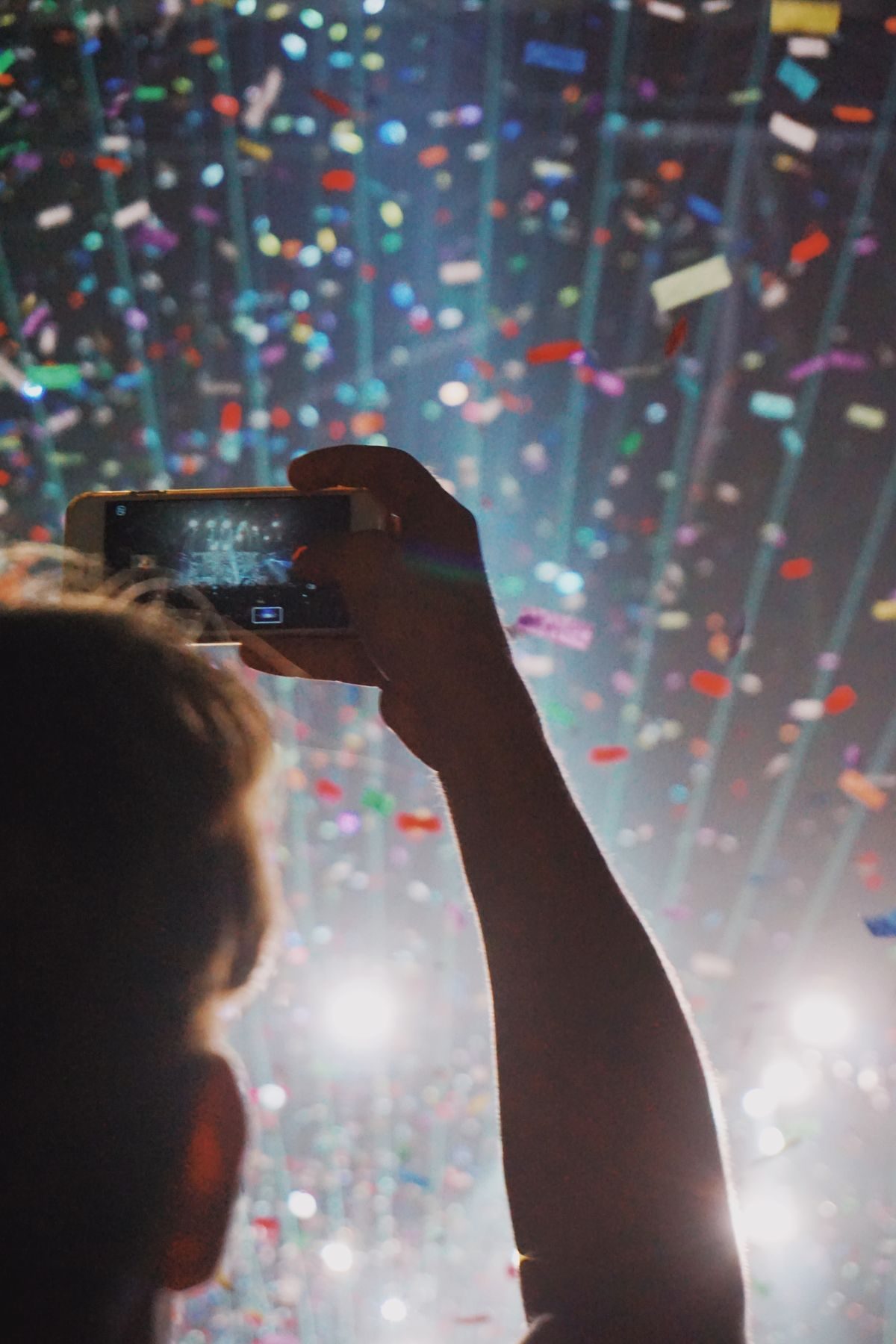 A phone held up to film confetti falling at a celebration